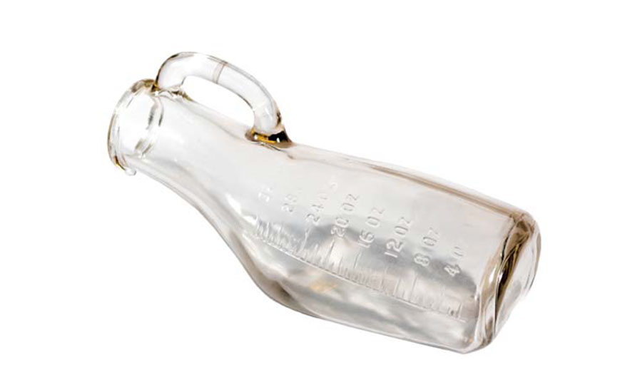 Orinal o cacho de vidrio. Tiene forma de una botella, solo que de un lado es recto y del otro, curvo. Del lado sin curva, tiene una agarradera con la misma forma que la oreja de una taza. A lo alto del cacho, tiene escritos con relieve los números para saber las medidas del líquido que se deposita dentro
